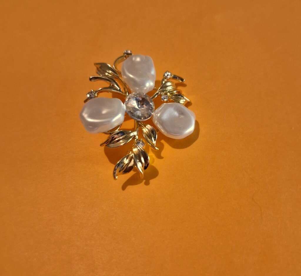 three petal pearl brooch on orange background