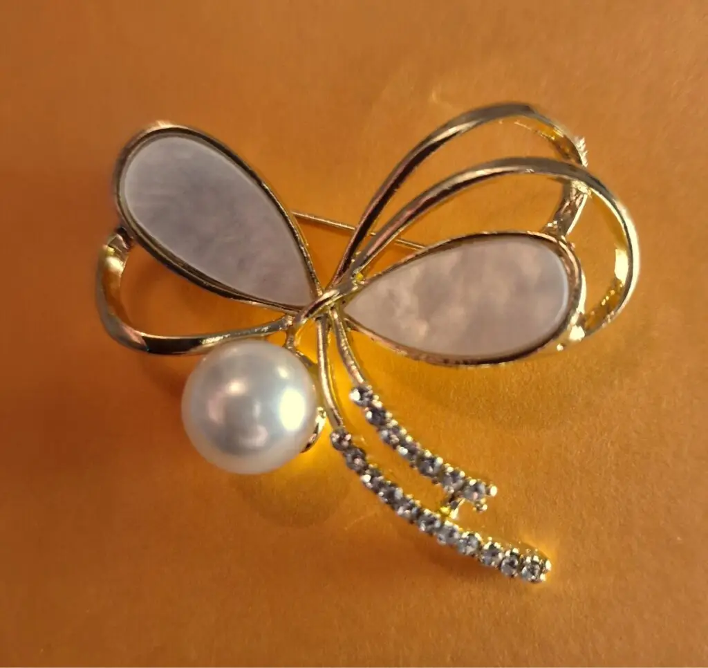 pearl bow brooch with diamonde detail on gold plated metal