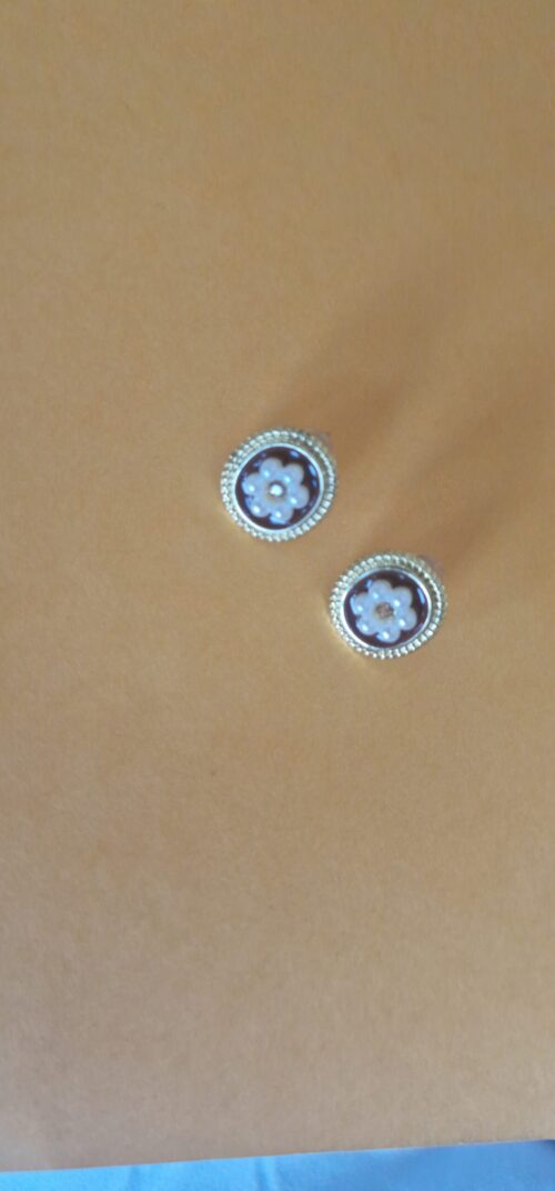Two flower pearl gold plated earrings with pearl detail on a orange background
