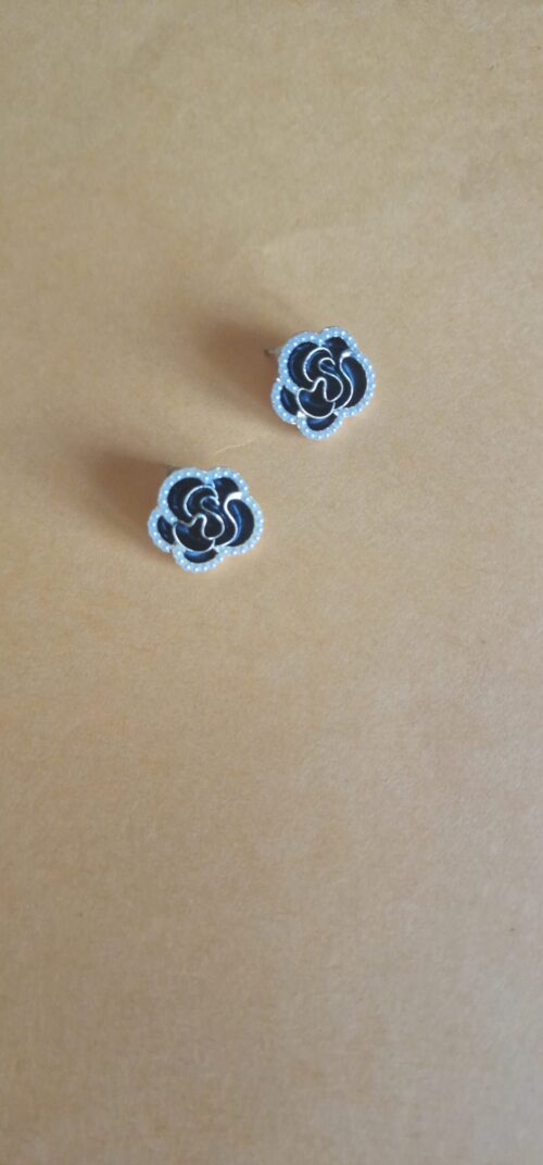 Black burgundy gold rose earrings with pearl detail on a orange background.