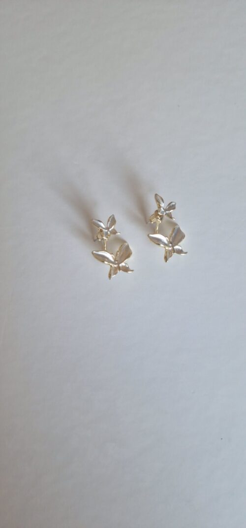 Double butterfly gold earrings with pearl detail on a white background.