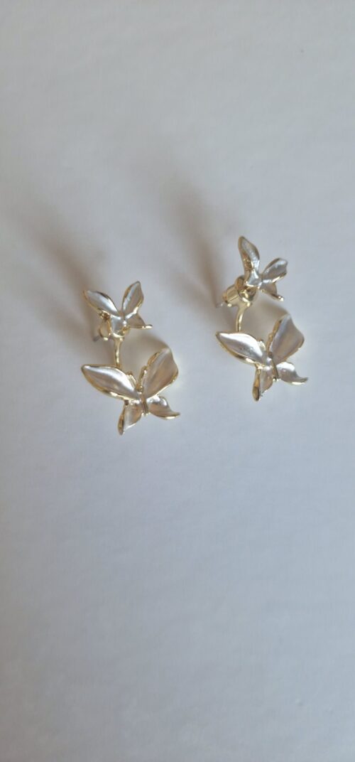 Double butterfly gold earrings with pearl detail on a white background.