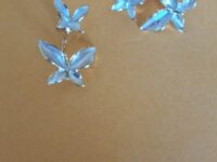 Double butterfly gold earrings with pearl detail on a orange background.