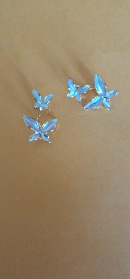 Double butterfly gold earrings with pearl detail on a orange background.