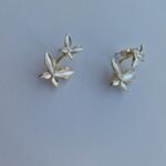 Double butterfly gold earrings with pearl detail on a white background.