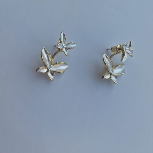 Double butterfly gold earrings with pearl detail on a white background.