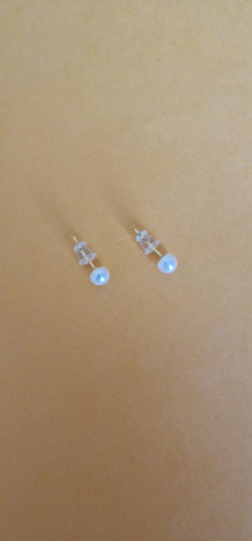 Two stud pearl silver earrings on a orange background