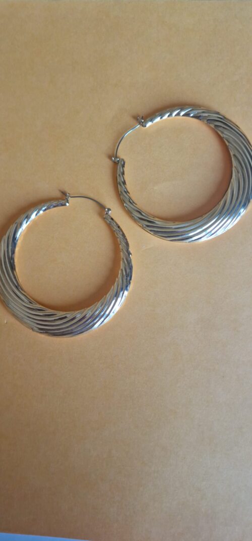Big statement gold hoop earrings on a orange background.
